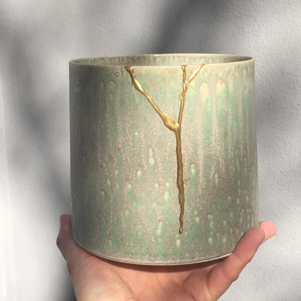 Grøn keramikurtepotte med skår er repareret med new kintsugi kit. Køb New kintsugi hos WAUW design online her.